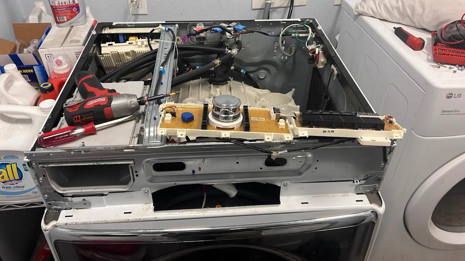 Front-load washer with the top off and the control board pulled out for repair